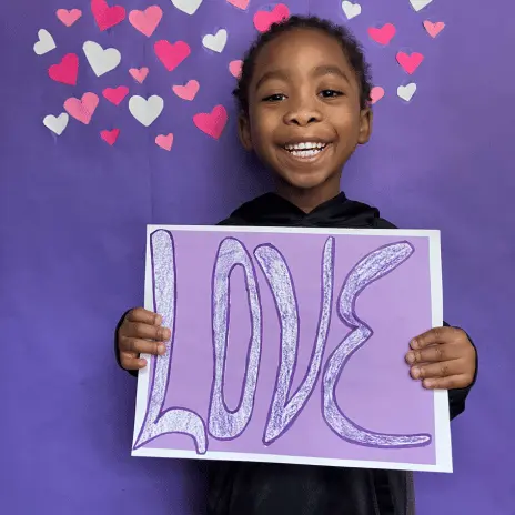 child holding sign at extraordinary kids